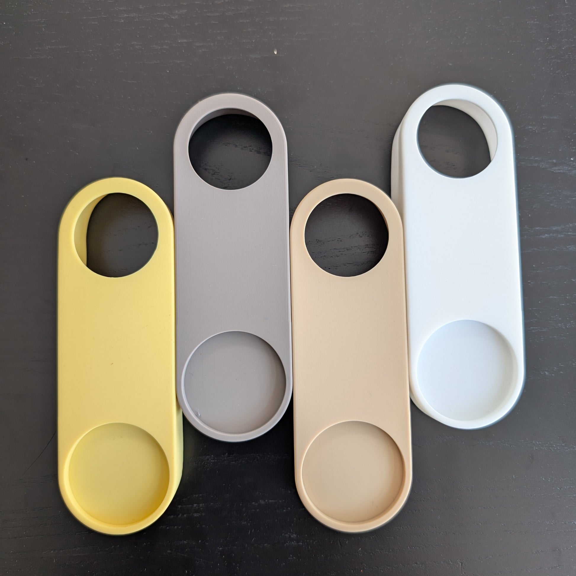 Four colorful bottle openers on a dark surface